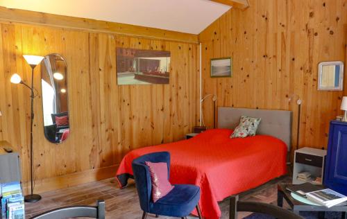- une chambre avec un lit rouge et une chaise bleue dans l'établissement Espace Nature Studio indépendant proche du Parc des oiseaux, à Sainte-Olive