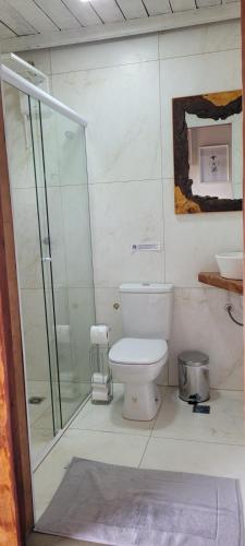 a bathroom with a toilet and a glass shower at Hospedagem Pé de Serra in Botucatu