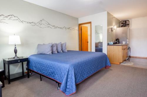 1 dormitorio con cama azul y baño en The Pioneer Motel, en Palmer