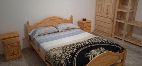 1 dormitorio con 1 cama de madera y 2 armarios de madera en Lo de la Nercida en Tornquist