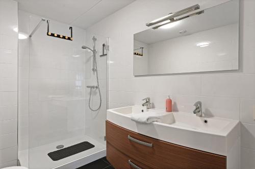 y baño blanco con lavabo y ducha. en Appartement Ibiza in Zeeland Kabbelaarsbank 411 Port Marina Zélande Ouddorp - not for companies, en Ouddorp