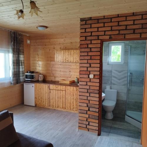 a bathroom with a toilet and a brick wall at Domki Letniskowe Meduza in Jarosławiec