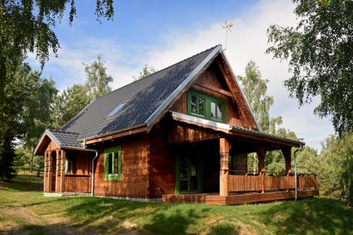 uma cabana de madeira com um telhado de gambrel em Domy Nad Drawskim em Siemczyno