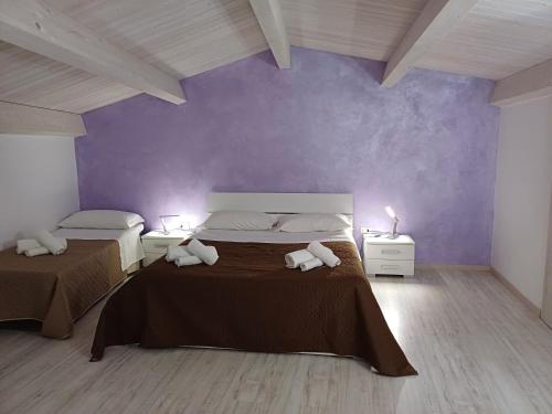 a bedroom with two beds and a purple wall at Casa Anna Maria in Marsala