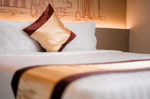 a bed with white pillows and a brown pillow at The Rangoon Hotel in Yangon