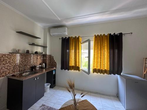 a kitchen with yellow curtains and a sink and a window at Koa Studio 1 in Korçë