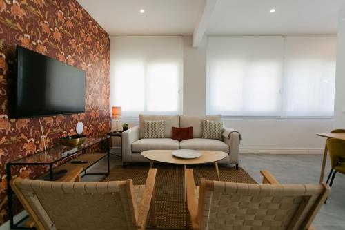 a living room with a couch and a tv at Lujoso apartamento con piscina compartida 3 in Seville