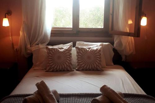 a bed with white sheets and pillows and a window at A Home away from Home in Psakoudia