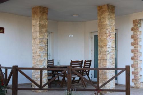 een eetkamer met 2 zuilen en een houten tafel bij Къща за гости Света Марина in Krapets