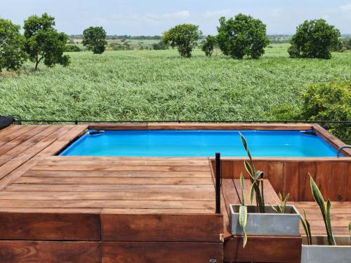 una piscina con una terraza de madera y un campo en Royal Tusker Hotel, en Udawalawe