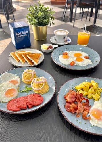 a table with three plates of breakfast food on it at Aparta Hotel Roma in Santo Domingo