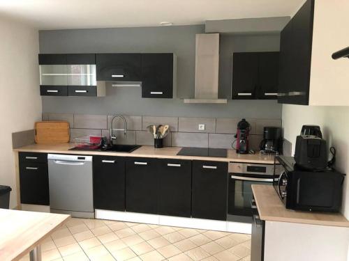 une cuisine avec des armoires noires et des appareils en acier inoxydable dans l'établissement maison individuelle, à Laveissière