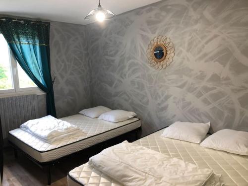 2 Einzelbetten in einem Zimmer mit einer Wand in der Unterkunft maison individuelle in Laveissière