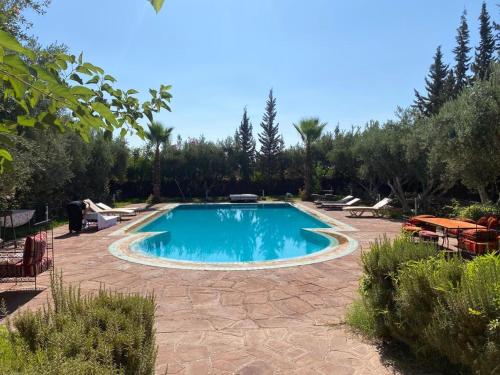 a swimming pool in a yard with chairs and trees at Riad Sidi Hicham in Marrakech