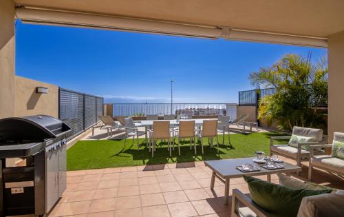 eine Terrasse mit einem Grill, einem Tisch und Stühlen in der Unterkunft Oasis del Mar in Puerto de Santiago