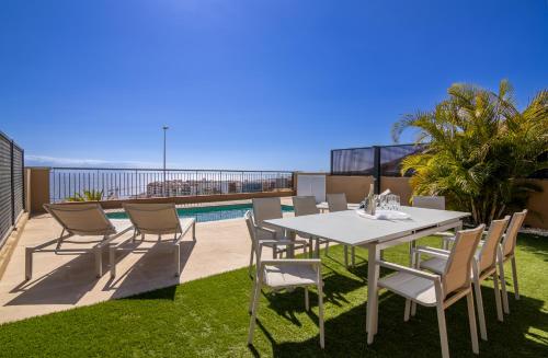 Une table à manger et des chaises blanches sont disponibles sur la terrasse. dans l'établissement Oasis del Mar, à Puerto de Santiago
