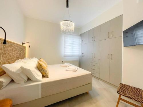 a bedroom with a bed with white cabinets and a chandelier at Just Live in Triovasálos