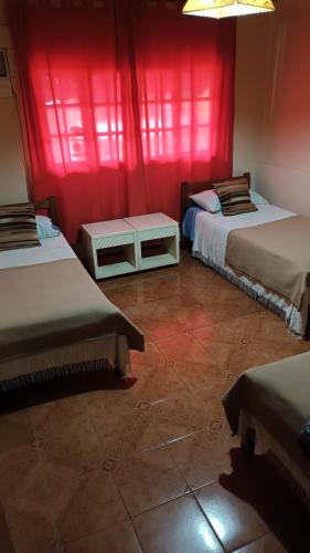 a room with two beds and red curtains at ALOJAMIENTO FAMILIAR in Puerto Iguazú