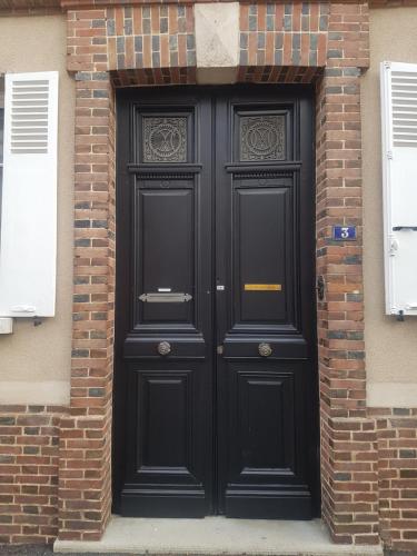 un par de puertas negras en un edificio de ladrillo en Le Clos Saint-Germain en Rugles