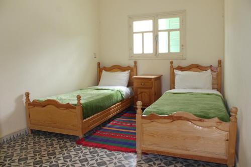 2 Einzelbetten in einem Zimmer mit Fenster in der Unterkunft Hotel Izlane in Imilchil