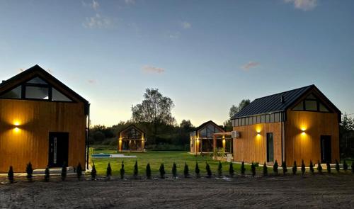 a group of three houses in a field at Bliżej Natury Stodoły, Domki na Mazurach in Świętajno