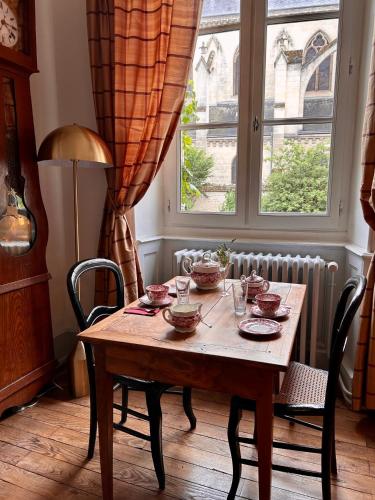 a wooden table with dishes on it in a room with a window at Maison Harmonie in La Châtre