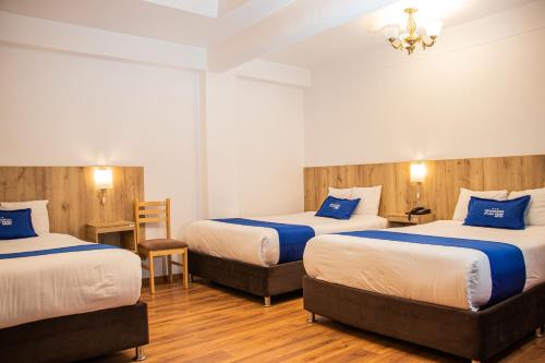 um quarto de hotel com duas camas e uma cadeira em Estancia San Pedro Hotel em Cusco
