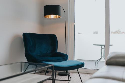 a blue chair in a living room with a lamp at Causeway Coast Sea Shore Apartment - Ballycastle in Ballycastle