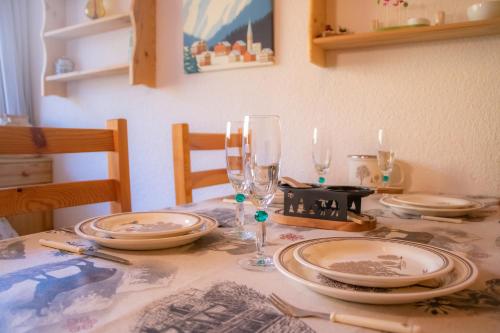 a table with plates and wine glasses on it at Le Rossane 26m Balcon vue in Aillon-le-Jeune