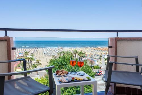 a table with wine glasses and a plate of food on a balcony at Parco dei Principi Boutique Hotel in Rimini