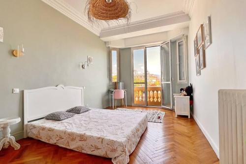 a white bedroom with a bed and a large window at Le Palais Riviera in Nice