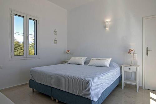 a white bedroom with a bed and a window at Villa Big Blue in Mavrovoúnion