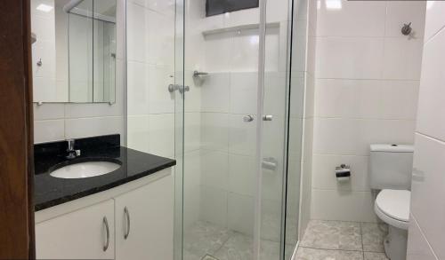 uma casa de banho com uma cabina de duche em vidro com um lavatório e um WC. em Hotel Itamaraty em Curitiba