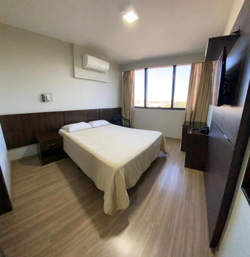 a hotel room with a bed and a large window at Hotel Itamaraty in Curitiba