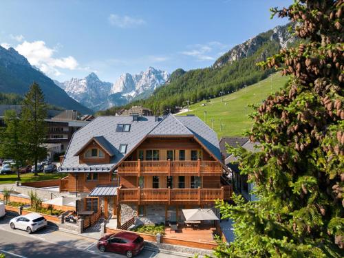 a large wooden house with mountains in the background at Vila Pavlina in Kranjska Gora