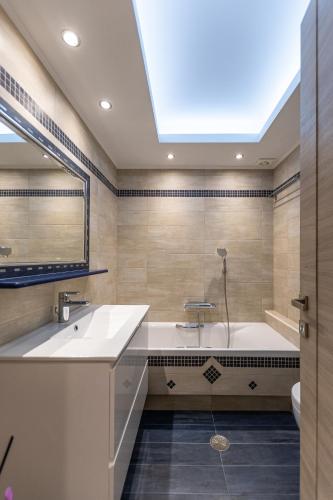 a bathroom with a tub and a sink and a mirror at Naxos Alma House in Naxos Chora