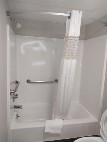 La salle de bains est pourvue d'une douche avec rideau de douche blanc. dans l'établissement Days Inn by Wyndham Vineland, à Vineland