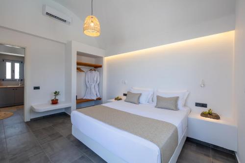 a bedroom with a large white bed and a bathroom at Bonsai Luxury Suites in Karterados
