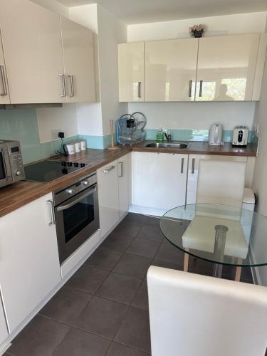 a kitchen with white cabinets and a glass table at Gunwharf Quays Harbour Apartments in Portsmouth