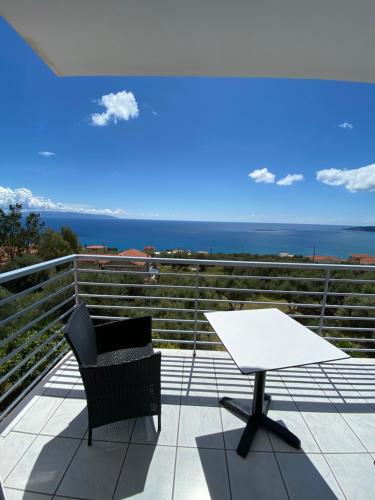a balcony with a table and a chair and the ocean at Odyseas Studios in Lourdhata