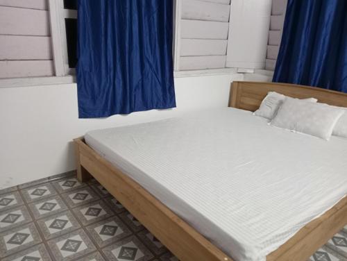 a bed in a room with a blue window at DOOARS VELLEY HOME STAY in Buxa Duār