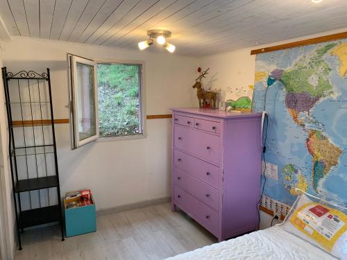 a bedroom with a purple dresser and a map on the wall at Chalet dans le vert in Gassin