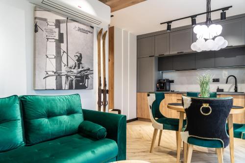 a living room with a green couch and a table at Apartament Niebiańska Polana by Apart Concept Podhale in Kościelisko