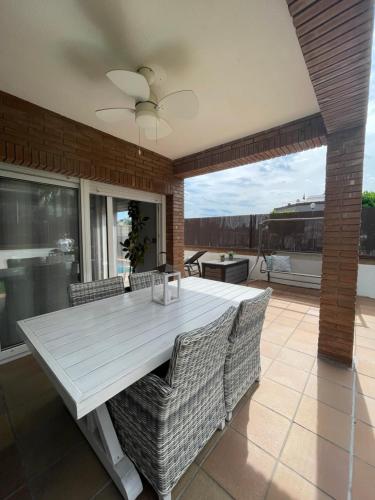 Une table à manger et des chaises blanches sont disponibles sur la terrasse. dans l'établissement Casa con piscina cerca de la playa, à Vidreres