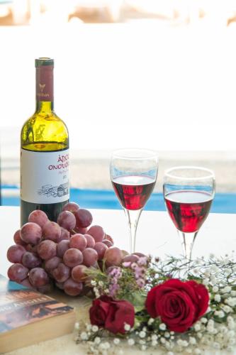 a bottle of wine and two glasses of red wine at Hill View Hotel Apartments in Pissouri