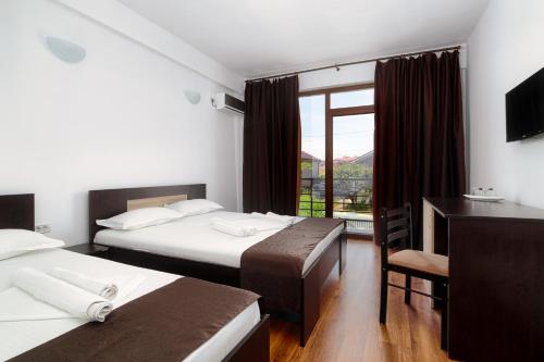 コスティネシュティにあるVila 21Aのベッド2台、デスク、窓が備わるホテルルームです。