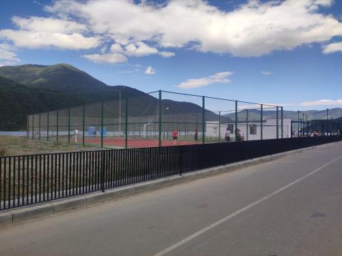a tennis court behind a fence on the side of a road at Ananuri Cottages in Ananuri