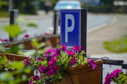 a blue parking sign sitting next to some flowers at Hotel Premium in Jajce