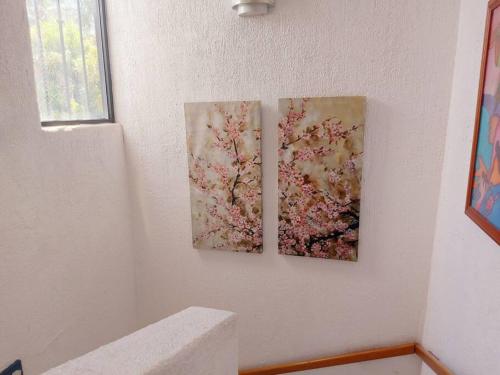 duas pinturas de flores numa parede branca em Casa en Club de Golf Santa Fe em Temixco