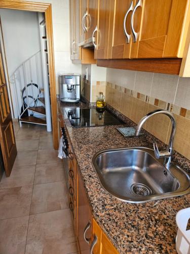 a kitchen with a stainless steel sink and wooden cabinets at Ático Pola in Santa Pola